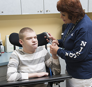 male high school student working with school nursse in nurses office