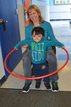 Young male student playing with a hula hoop with teacher - private special educations school NJEDDA Passaic NJ