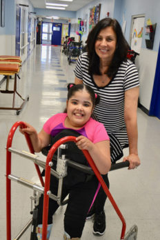 Young female student using walker with teacher - NJEDDA Passaic NJ - private special education school