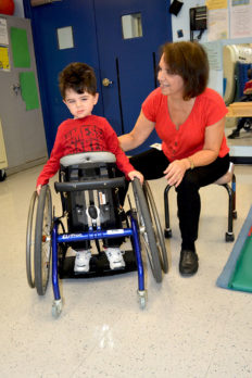 Young male preschool student in wheeled mobility device with female teacher at North Jersey Elks Developmental Disabilities Agency