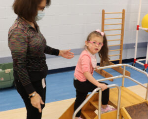 Physical Thera[ist working with a young femaile student with developmental disabilities on stair climbing and strength