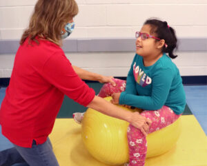 Occup[ational therapist working with female Elementary student on sitting and balancing
