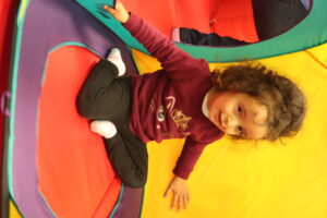 young female toddler with disabilities playing in a folding tent structure
