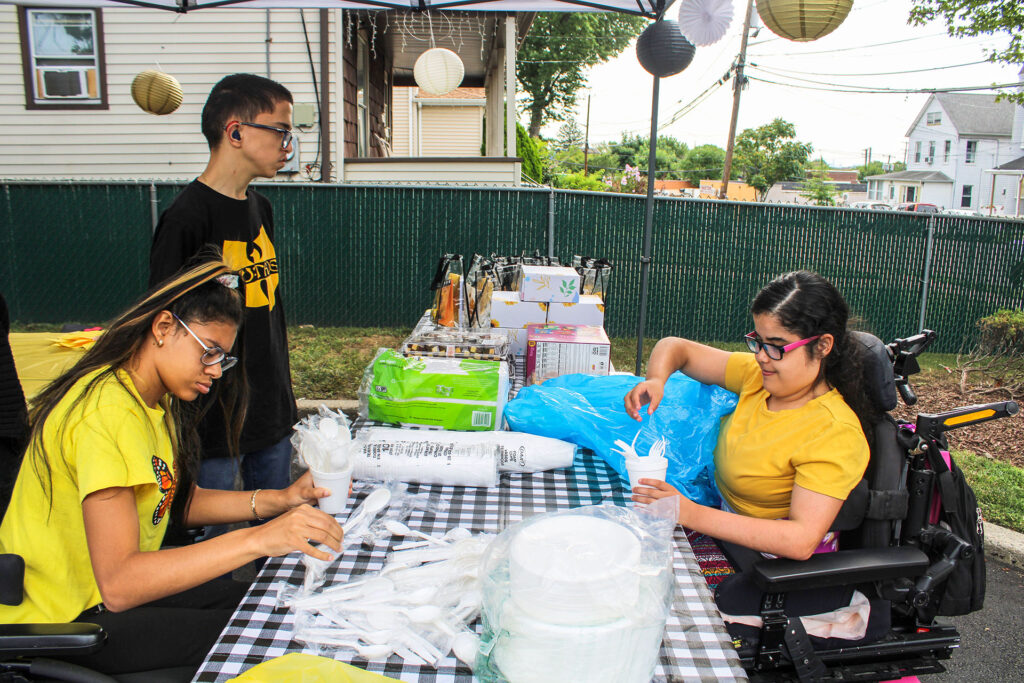 Three NJEDDA students preparing for a picnic at an outdoor picnic table 