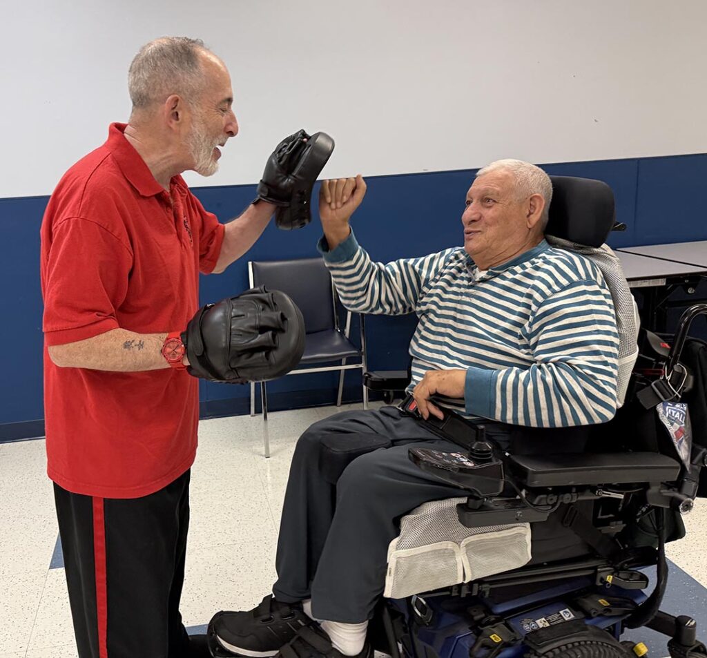 Adult Center Pic 2-redux Older male NJEDDA Adult Training Center participant practicing punching with a therapist wearing training gloves.