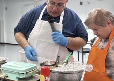NJEDDA Adult Center staff person teaching a program participant how to make waffles