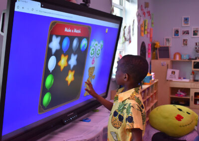A young male NJEDDA student working on visual matching on a large classroom touchscreen.